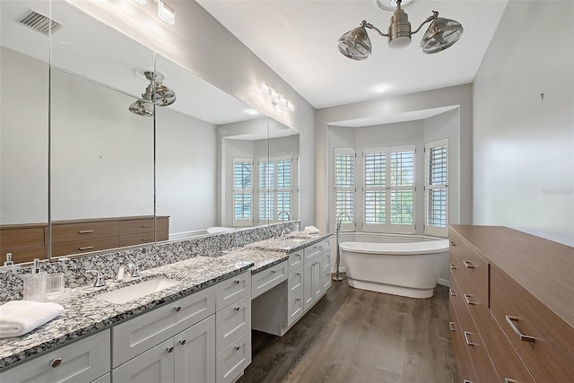 7868 Chick Evans Pl, Sarasota, FL 34240 - full bathroom with wood finished floors, vanity, a freestanding tub, and a chandelier
