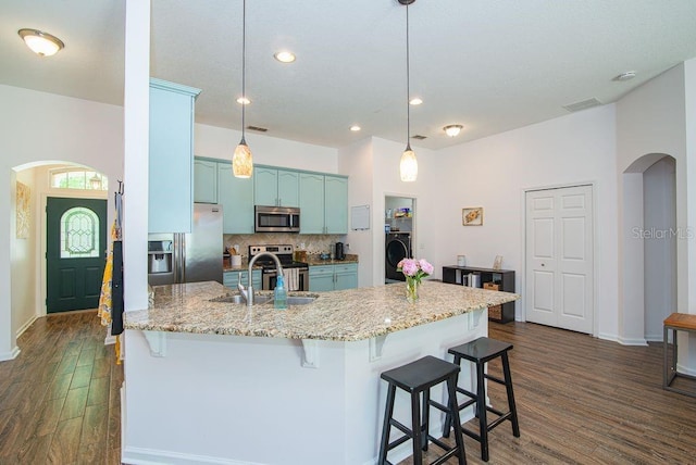 572 Sparrow Branch Cir, Saint Johns, FL 32259 - kitchen featuring appliances with stainless steel finishes, arched walkways, washer / dryer, dark wood-style floors, and a breakfast bar area