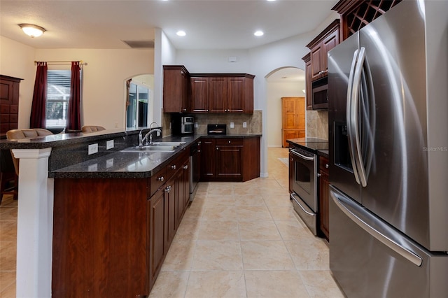 5242 Abdella Ln, North Port, FL 34291 - kitchen featuring stainless steel appliances, arched walkways, backsplash, a peninsula, and light tile patterned floors