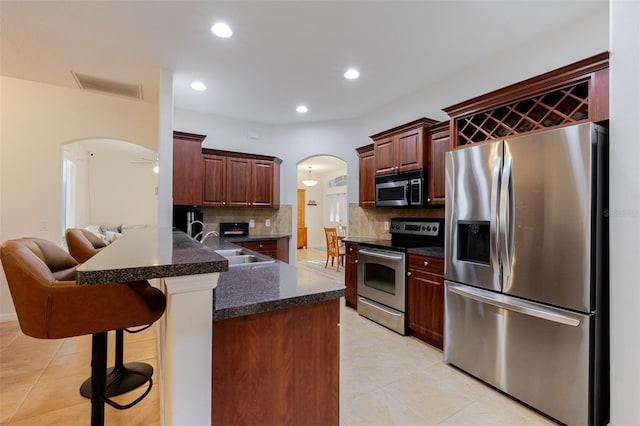 5242 Abdella Ln, North Port, FL 34291 - kitchen with stainless steel appliances, arched walkways, tasteful backsplash, a breakfast bar, and light tile patterned floors