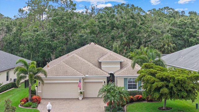 12215 Goldenrod Ave, Bradenton, FL 34212 - view of front of property with a garage, driveway, stucco siding, a front lawn, and a shingled roof