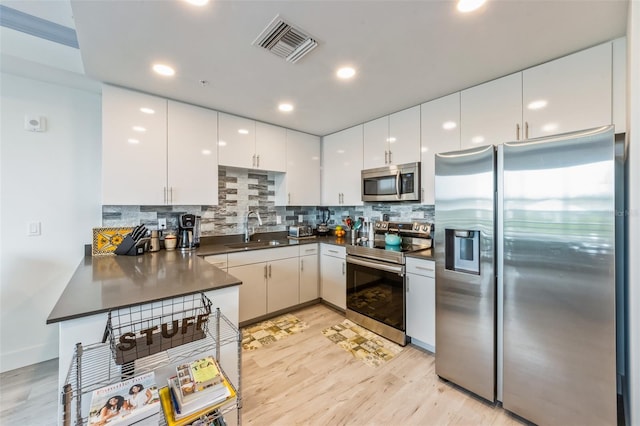 1709 N Tamiami Trl Unit A313, Sarasota, FL 34234 - kitchen featuring stainless steel appliances, dark countertops, light wood-style flooring, tasteful backsplash, and recessed lighting