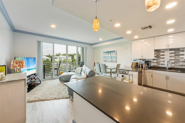 1709 N Tamiami Trl Unit A313, Sarasota, FL 34234 - kitchen featuring light wood finished floors, decorative backsplash, open floor plan, dark countertops, and white cabinetry