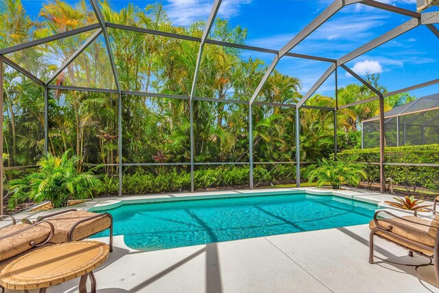 7314 Wexford Ct, Lakewood Ranch, FL 34202 - outdoor pool with a patio area, glass enclosure, and view of wooded area