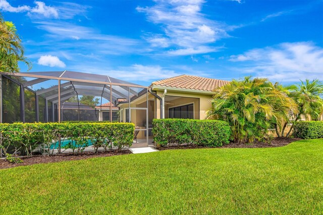 7314 Wexford Ct, Lakewood Ranch, FL 34202 - rear view of house with a lawn, a tile roof, a lanai, an outdoor pool, and stucco siding
