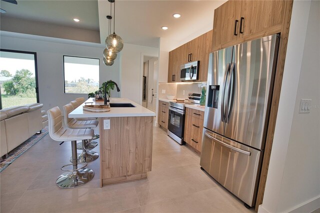 366 Fordham Rd, Venice, FL 34293 - kitchen featuring stainless steel appliances, light countertops, brown cabinets, a center island with sink, and modern cabinets
