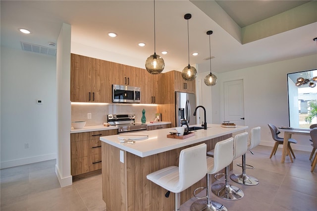 366 Fordham Rd, Venice, FL 34293 - kitchen with stainless steel appliances, modern cabinets, brown cabinetry, a center island with sink, and light countertops