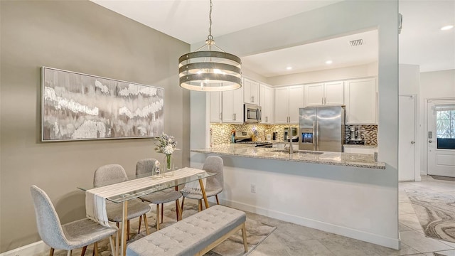 15160 Lyla Ter, Bradenton, FL 34211 - kitchen featuring stainless steel appliances, backsplash, white cabinetry, a peninsula, and light stone counters