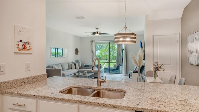 15160 Lyla Ter, Bradenton, FL 34211 - kitchen featuring open floor plan, ceiling fan, light stone countertops, white cabinets, and decorative light fixtures
