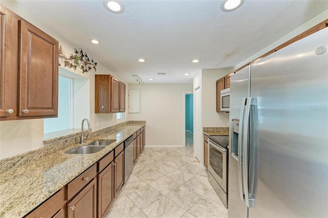 557 Reading St NW, Port Charlotte, FL 33952 - kitchen with appliances with stainless steel finishes, light stone countertops, brown cabinetry, recessed lighting, and a textured ceiling