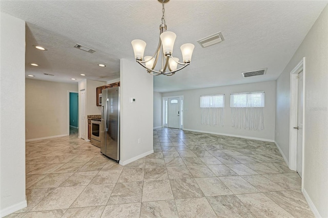 557 Reading St NW, Port Charlotte, FL 33952 - kitchen with freestanding refrigerator, a chandelier, a textured ceiling, pendant lighting, and stove