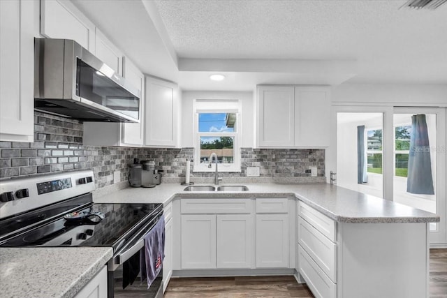 5401 Mac Arthur Ave, New Port Richey, FL 34652 - kitchen featuring appliances with stainless steel finishes, a peninsula, wood finished floors, plenty of natural light, and a textured ceiling