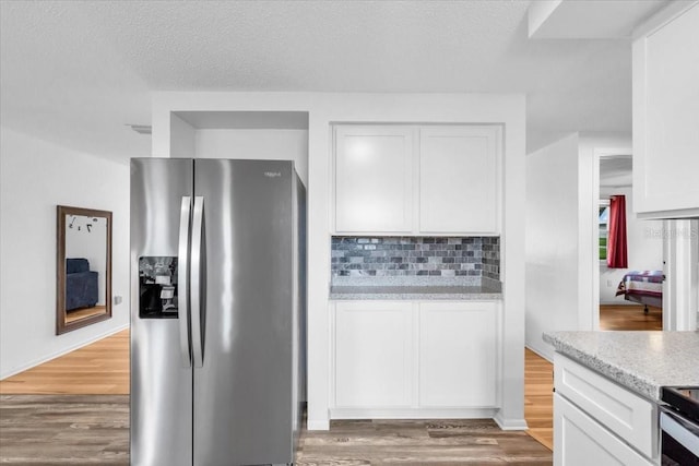 5401 Mac Arthur Ave, New Port Richey, FL 34652 - kitchen featuring stainless steel appliances, white cabinets, wood finished floors, tasteful backsplash, and light stone countertops