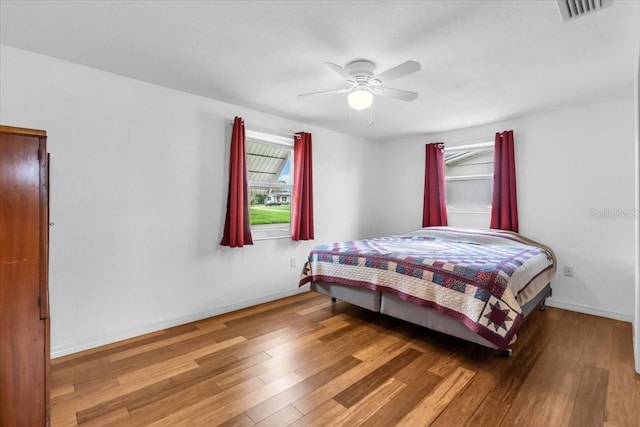5401 Mac Arthur Ave, New Port Richey, FL 34652 - bedroom featuring multiple windows, wood finished floors, and a ceiling fan