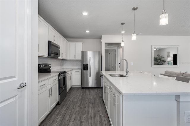 9144 Royal River Cir, Parrish, FL 34219 - kitchen with stainless steel appliances, white cabinets, pendant lighting, dark wood-style floors, and a center island with sink