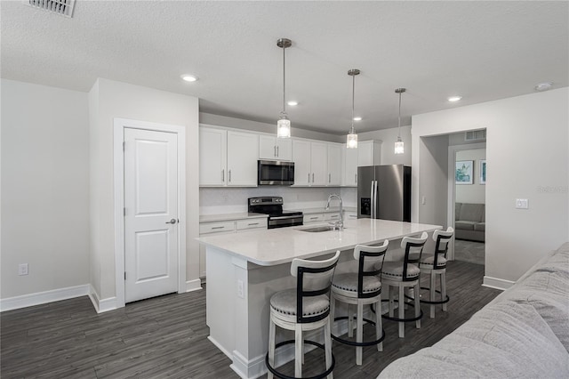 9144 Royal River Cir, Parrish, FL 34219 - kitchen with appliances with stainless steel finishes, dark wood-style floors, white cabinetry, a kitchen breakfast bar, and light countertops