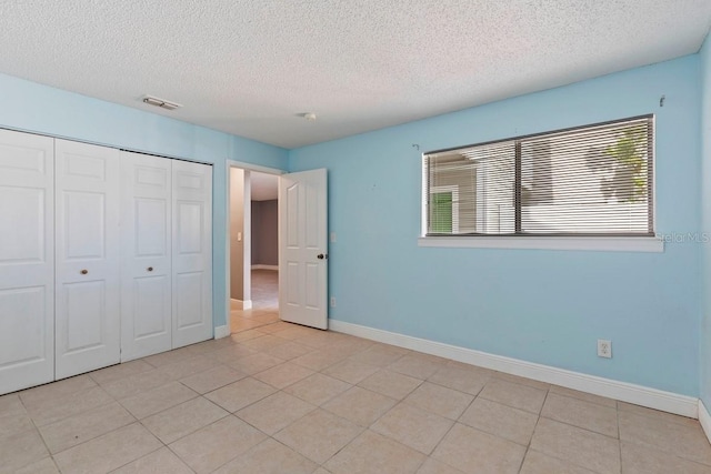 7298 Ulmerton Rd Unit 202, Largo, FL 33771 - unfurnished bedroom with a textured ceiling, multiple windows, a closet, and light tile patterned flooring