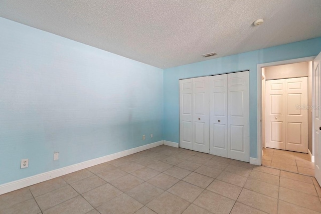 7298 Ulmerton Rd Unit 202, Largo, FL 33771 - unfurnished bedroom featuring light tile patterned floors, a textured ceiling, and a closet