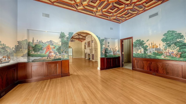 4423 Bay Shore Rd, Sarasota, FL 34234 - unfurnished room with coffered ceiling, arched walkways, a high ceiling, light wood finished floors, and beamed ceiling