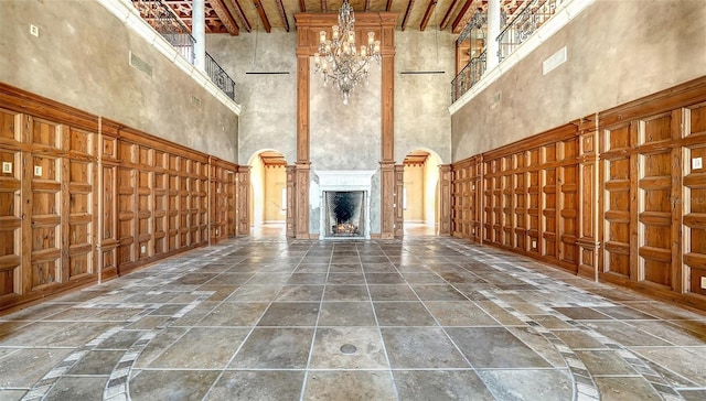 4423 Bay Shore Rd, Sarasota, FL 34234 - unfurnished living room featuring a high ceiling, stone tile flooring, arched walkways, a fireplace, and a chandelier