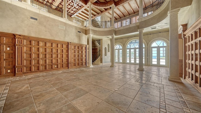 4423 Bay Shore Rd, Sarasota, FL 34234 - unfurnished living room featuring decorative columns, plenty of natural light, a high ceiling, stone tile floors, and beamed ceiling