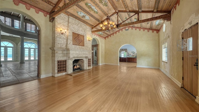 4423 Bay Shore Rd, Sarasota, FL 34234 - unfurnished living room with high vaulted ceiling, a chandelier, beam ceiling, light wood-style flooring, and a large fireplace