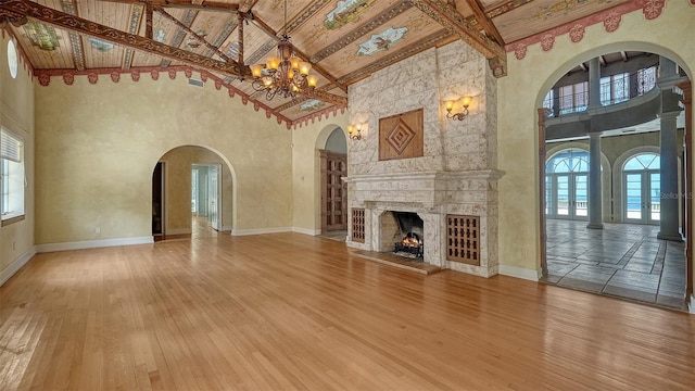 4423 Bay Shore Rd, Sarasota, FL 34234 - unfurnished living room with high vaulted ceiling, a chandelier, hardwood / wood-style floors, beamed ceiling, and a large fireplace