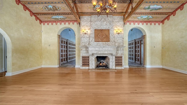 4423 Bay Shore Rd, Sarasota, FL 34234 - unfurnished living room featuring wood finished floors, beamed ceiling, a chandelier, arched walkways, and a fireplace