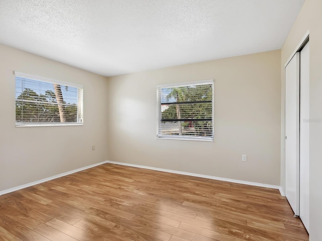 2423 Flamingo Blvd Unit K29, Bradenton, FL 34207 - unfurnished bedroom featuring multiple windows, light wood finished floors, a closet, and a textured ceiling