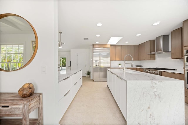 311 Island Cir, Sarasota, FL 34242 - kitchen with appliances with stainless steel finishes, wall chimney exhaust hood, modern cabinets, a skylight, and light stone counters
