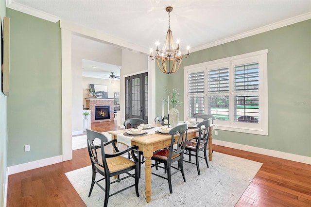 1906 143rd Ct E, Bradenton, FL 34212 - dining space featuring a fireplace, crown molding, a chandelier, wood finished floors, and a ceiling fan