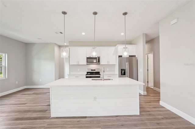 5534 Fairlane Dr, North Port, FL 34288 - kitchen featuring appliances with stainless steel finishes, an island with sink, white cabinets, light countertops, and light wood-style flooring