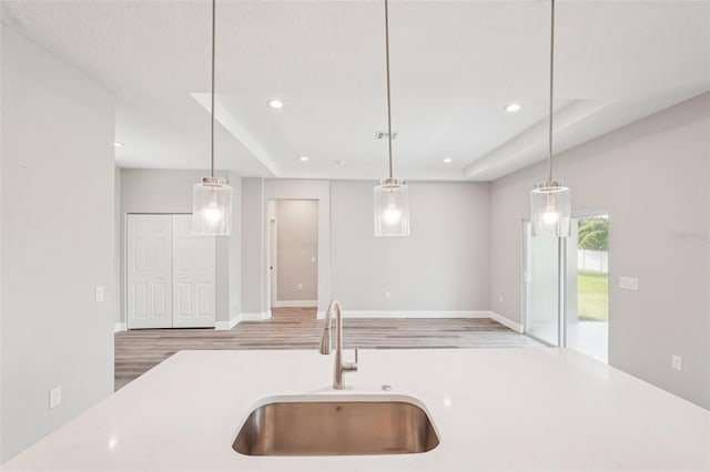 5534 Fairlane Dr, North Port, FL 34288 - kitchen featuring light countertops, recessed lighting, light wood-style flooring, hanging light fixtures, and a raised ceiling