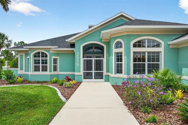 2555 Pear St, Port Charlotte, FL 33948 - view of exterior entry featuring stucco siding and a shingled roof