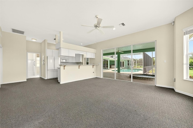 2555 Pear St, Port Charlotte, FL 33948 - unfurnished living room featuring a ceiling fan, dark carpet, and healthy amount of natural light