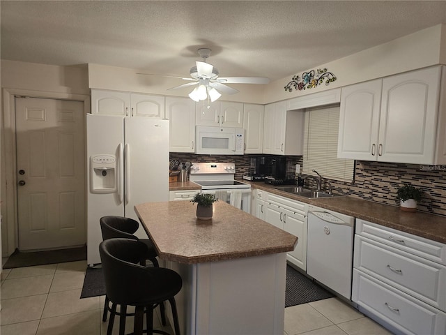 1903 4th Ave W, Palmetto, FL 34221 - kitchen featuring white appliances, light tile patterned floors, ceiling fan, a kitchen bar, and white cabinets