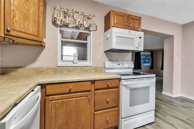 6439 Lafayette Rd, Bradenton, FL 34207 - kitchen featuring white appliances, light wood-style flooring, brown cabinetry, and light countertops