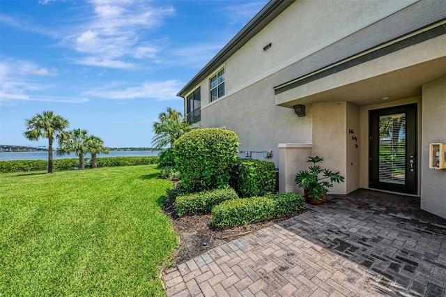 1226 Riverscape St, Bradenton, FL 34208 - doorway to property with a water view, stucco siding, a lawn, and a patio