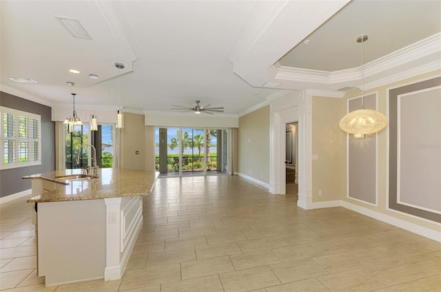 1226 Riverscape St, Bradenton, FL 34208 - kitchen with crown molding, a kitchen island with sink, healthy amount of natural light, light stone countertops, and open floor plan