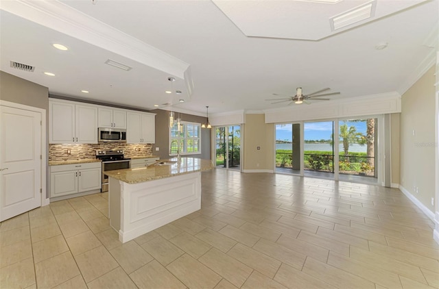 1226 Riverscape St, Bradenton, FL 34208 - kitchen featuring stainless steel appliances, ornamental molding, open floor plan, backsplash, and a ceiling fan