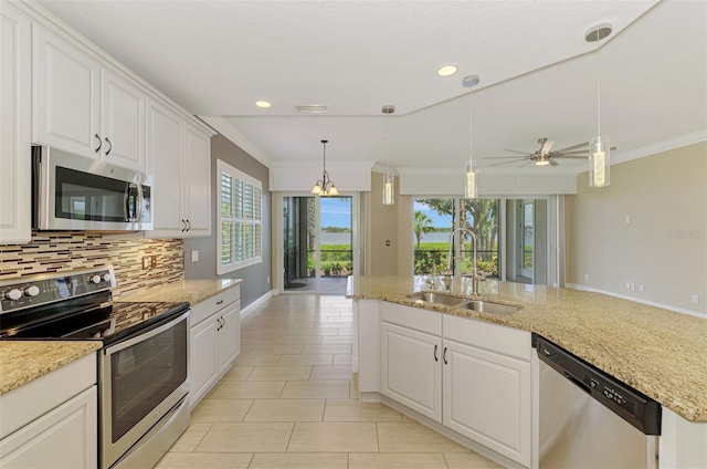 1226 Riverscape St, Bradenton, FL 34208 - kitchen featuring stainless steel appliances, backsplash, white cabinetry, hanging light fixtures, and ornamental molding