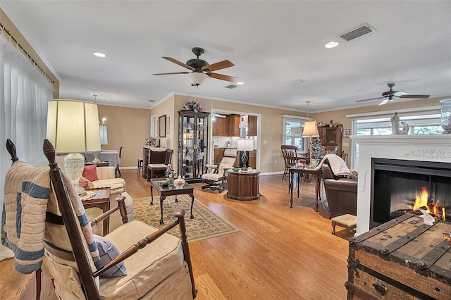 1907 76th St NW, Bradenton, FL 34209 - living room with a ceiling fan, light wood-style flooring, a warm lit fireplace, ornamental molding, and recessed lighting