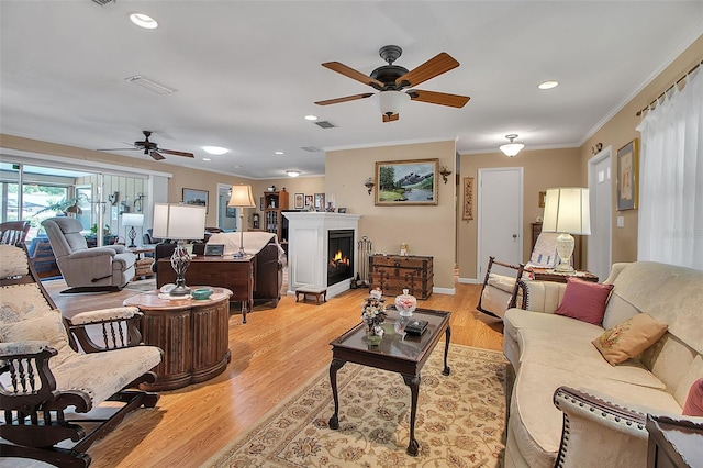 1907 76th St NW, Bradenton, FL 34209 - living room with a ceiling fan, crown molding, light wood-style flooring, a warm lit fireplace, and recessed lighting