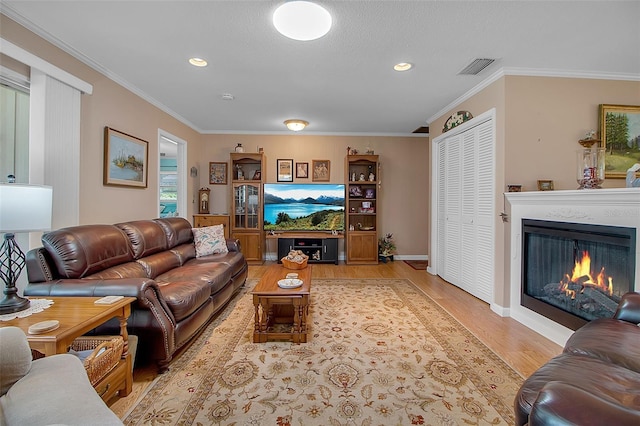 1907 76th St NW, Bradenton, FL 34209 - living room with wood finished floors, ornamental molding, a glass covered fireplace, and recessed lighting