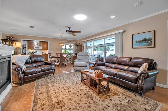 1907 76th St NW, Bradenton, FL 34209 - living area featuring ceiling fan, light wood finished floors, a fireplace, ornamental molding, and recessed lighting