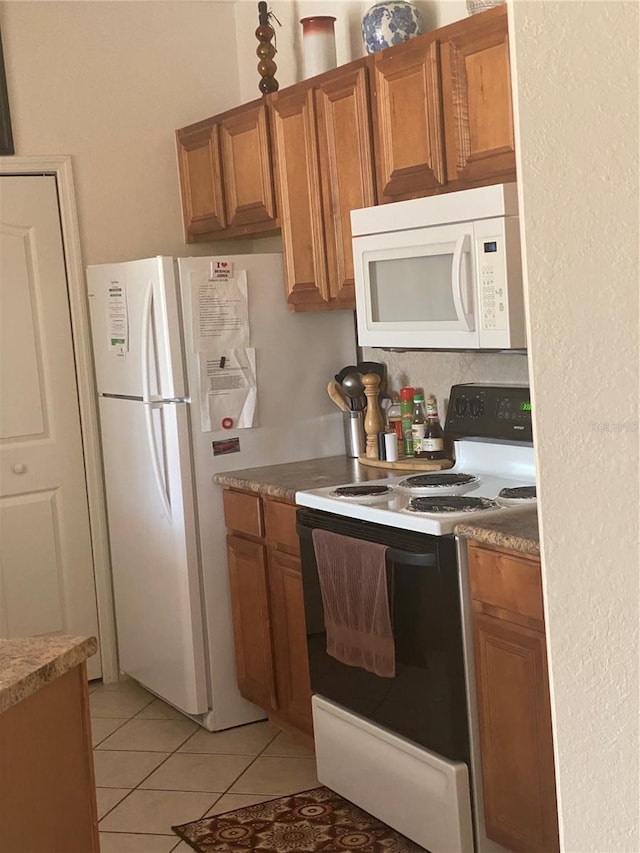 8397 38th Street Cir E Unit 305, Sarasota, FL 34243 - kitchen featuring white appliances, brown cabinetry, light tile patterned floors, and light countertops