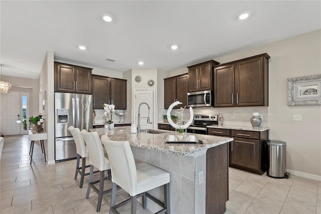 5313 Halewood Ct, Lakewood Ranch, FL 34211 - kitchen with stainless steel appliances, dark brown cabinets, tasteful backsplash, a breakfast bar area, and recessed lighting