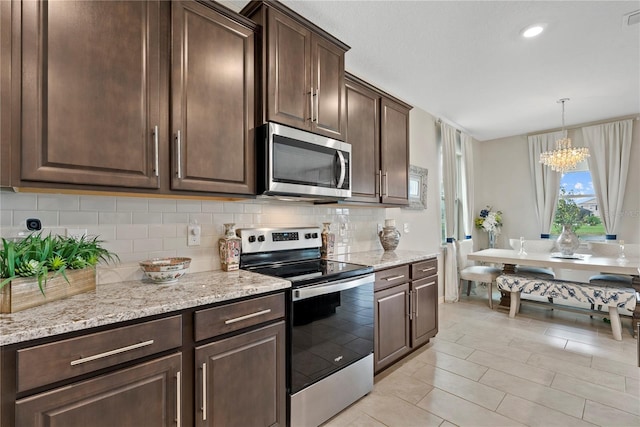 5313 Halewood Ct, Lakewood Ranch, FL 34211 - kitchen with stainless steel appliances, a chandelier, decorative backsplash, dark brown cabinets, and light stone counters