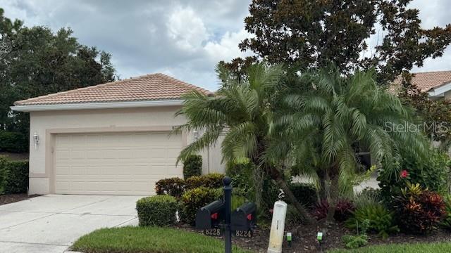 8228 Simpson Falls Ct, Sarasota, FL 34243 - view of front of home featuring a tile roof, driveway, stucco siding, and an attached garage