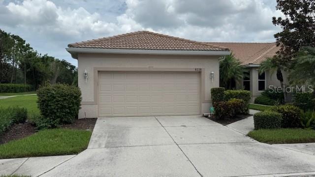 8228 Simpson Falls Ct, Sarasota, FL 34243 - view of front of property featuring concrete driveway, a tile roof, a garage, and stucco siding
